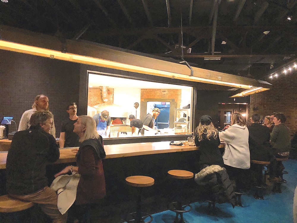 IT’S NOT TV: A view of the kitchen zoo from the bar at Ammazza. Photo by Cliff Bostock.