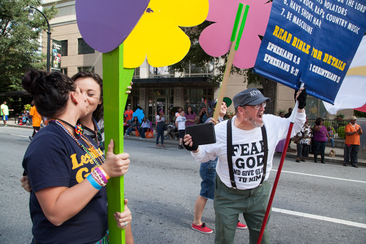 Attendees kiss in front of a protester.