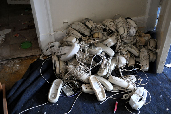 In the corner of one room, abandoned telephones have been tossed into a pile next to scattered glow sticks and old televisions. Photo by Joeff Davis.